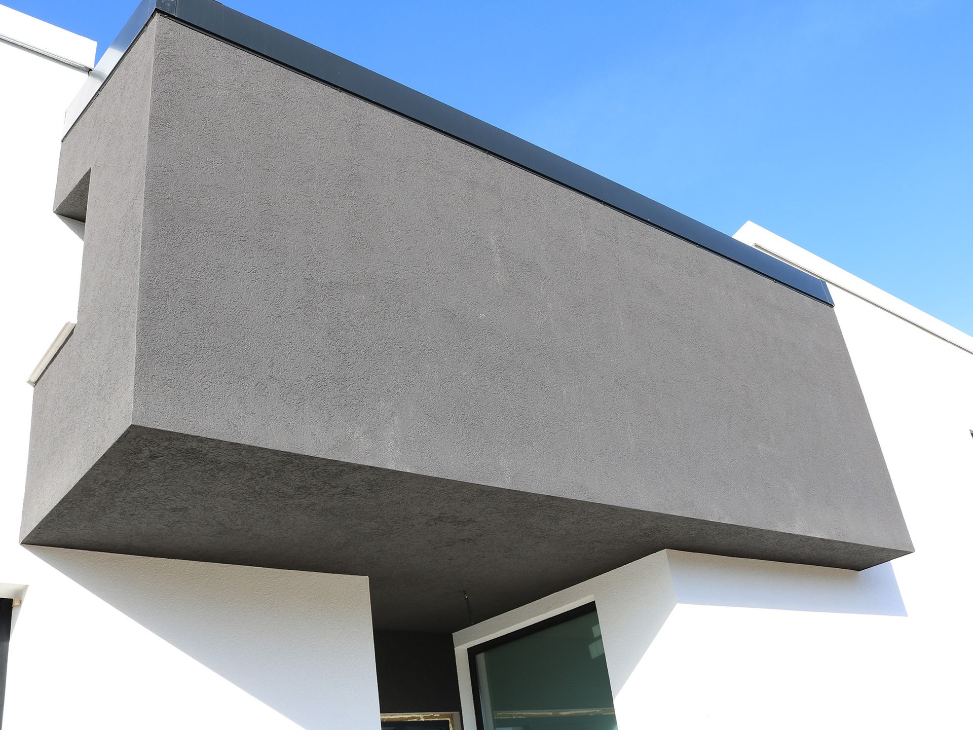 Un edificio gris y blanco con un cielo azul al fondo.