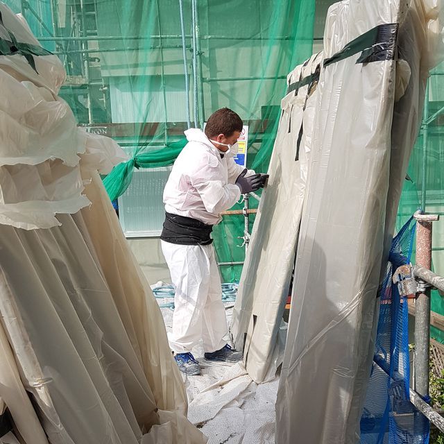 Un hombre con una máscara está trabajando en un edificio.