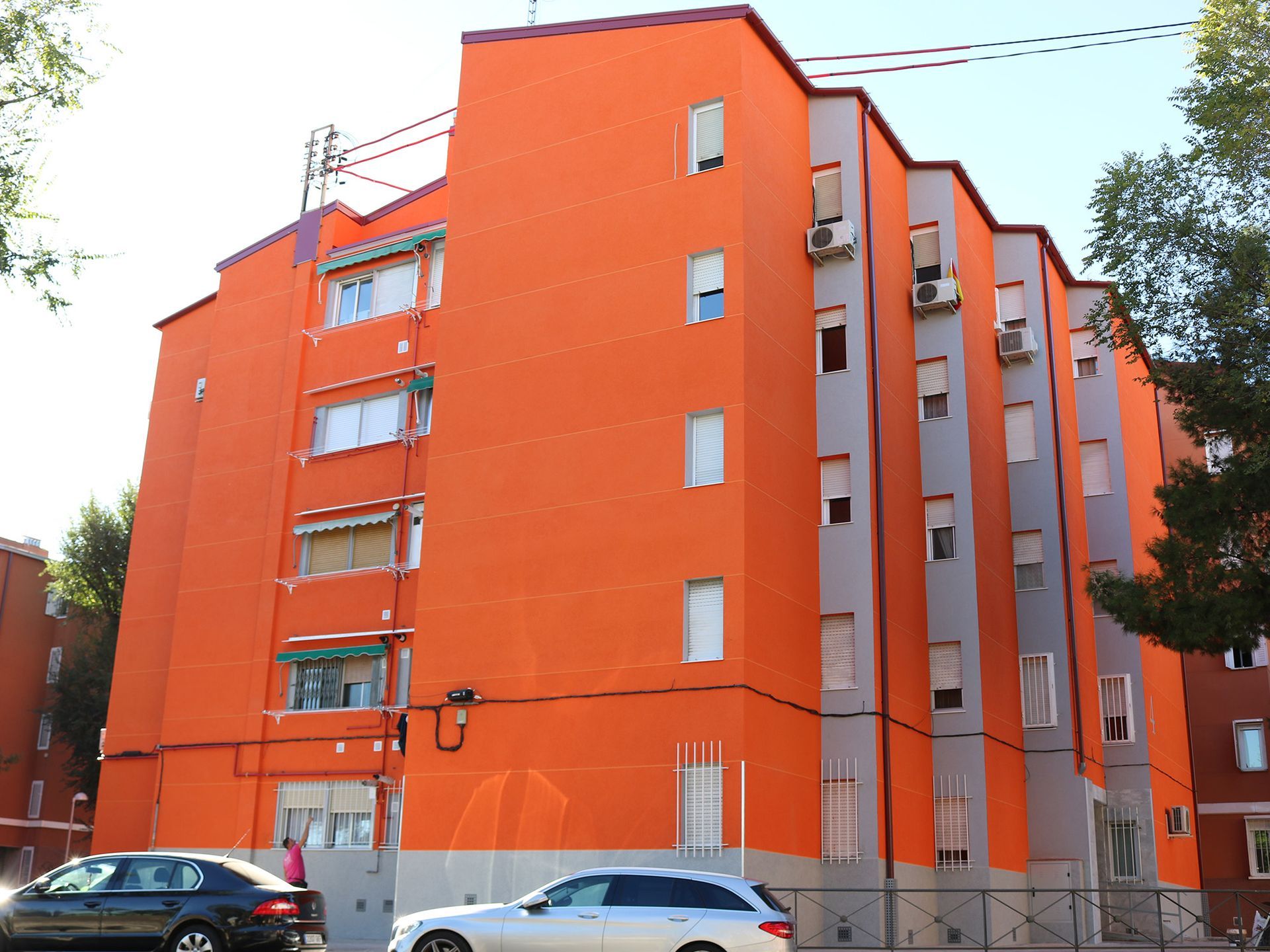 Un gran edificio naranja con coches aparcados delante.