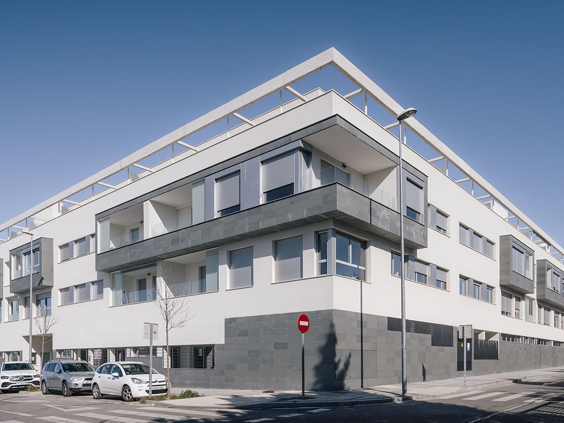 Un gran edificio blanco con coches aparcados delante.