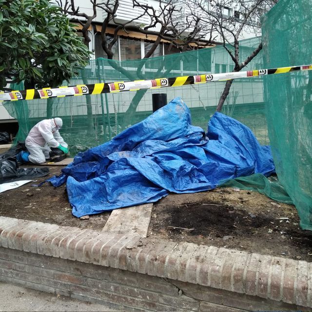 Un hombre con traje protector trabaja en una pila de lonas azules.