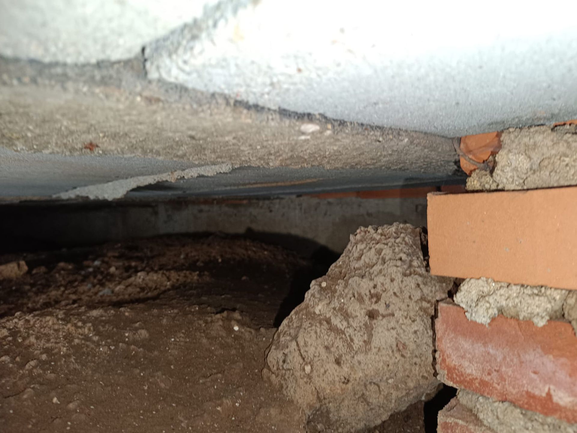 Hay una pared de ladrillos al fondo y una pared de hormigón en primer plano.