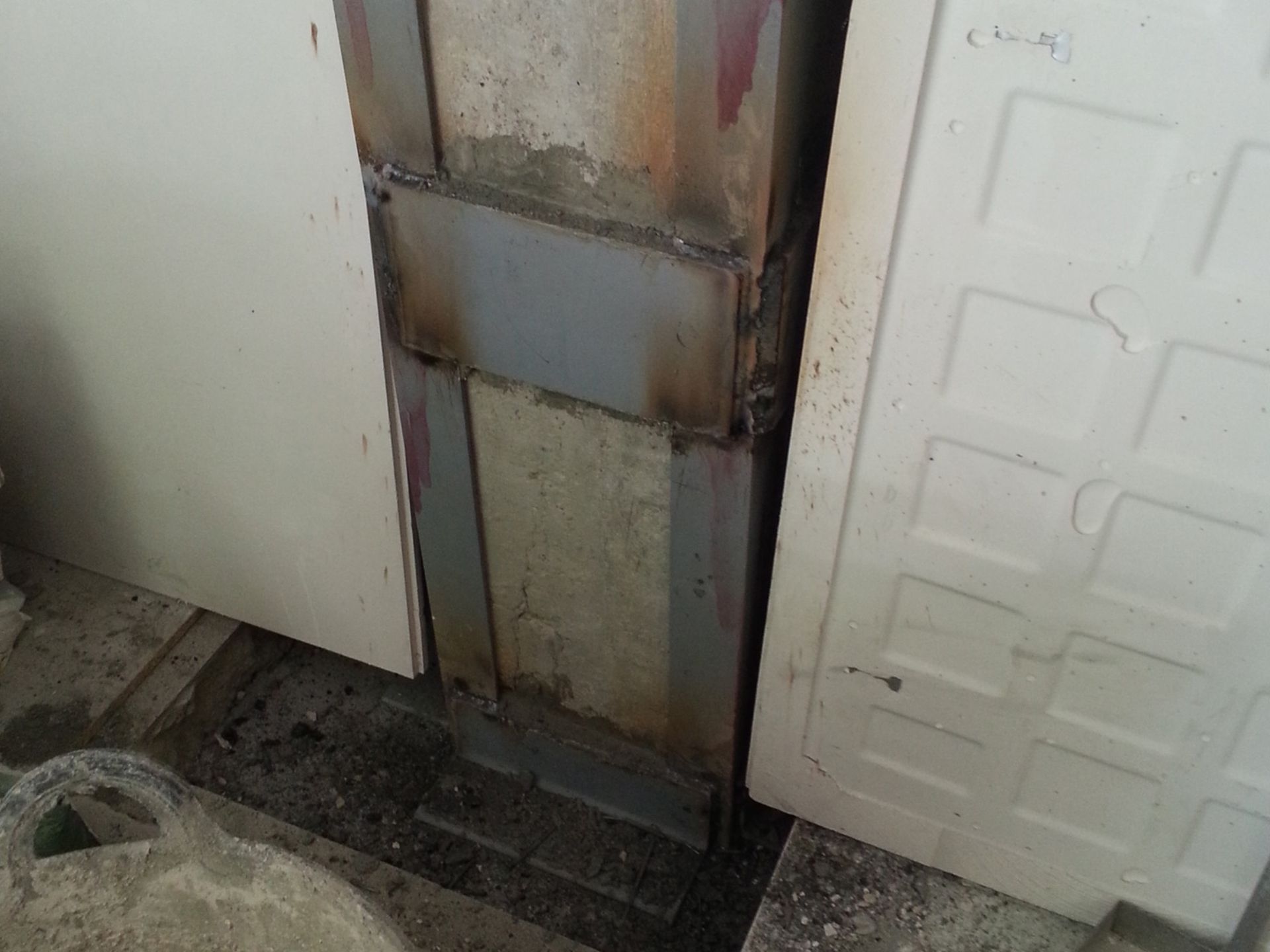 Una puerta de metal está al lado de una puerta blanca en una habitación.