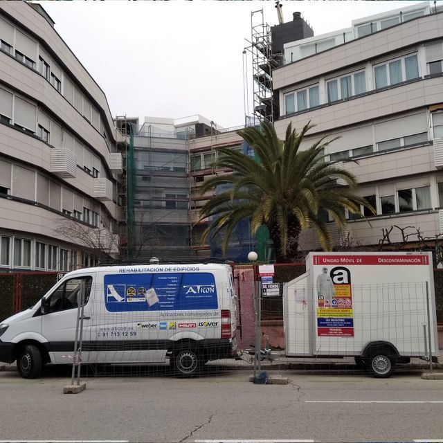 Una camioneta blanca con la palabra atlas en el costado está estacionada frente a un edificio.