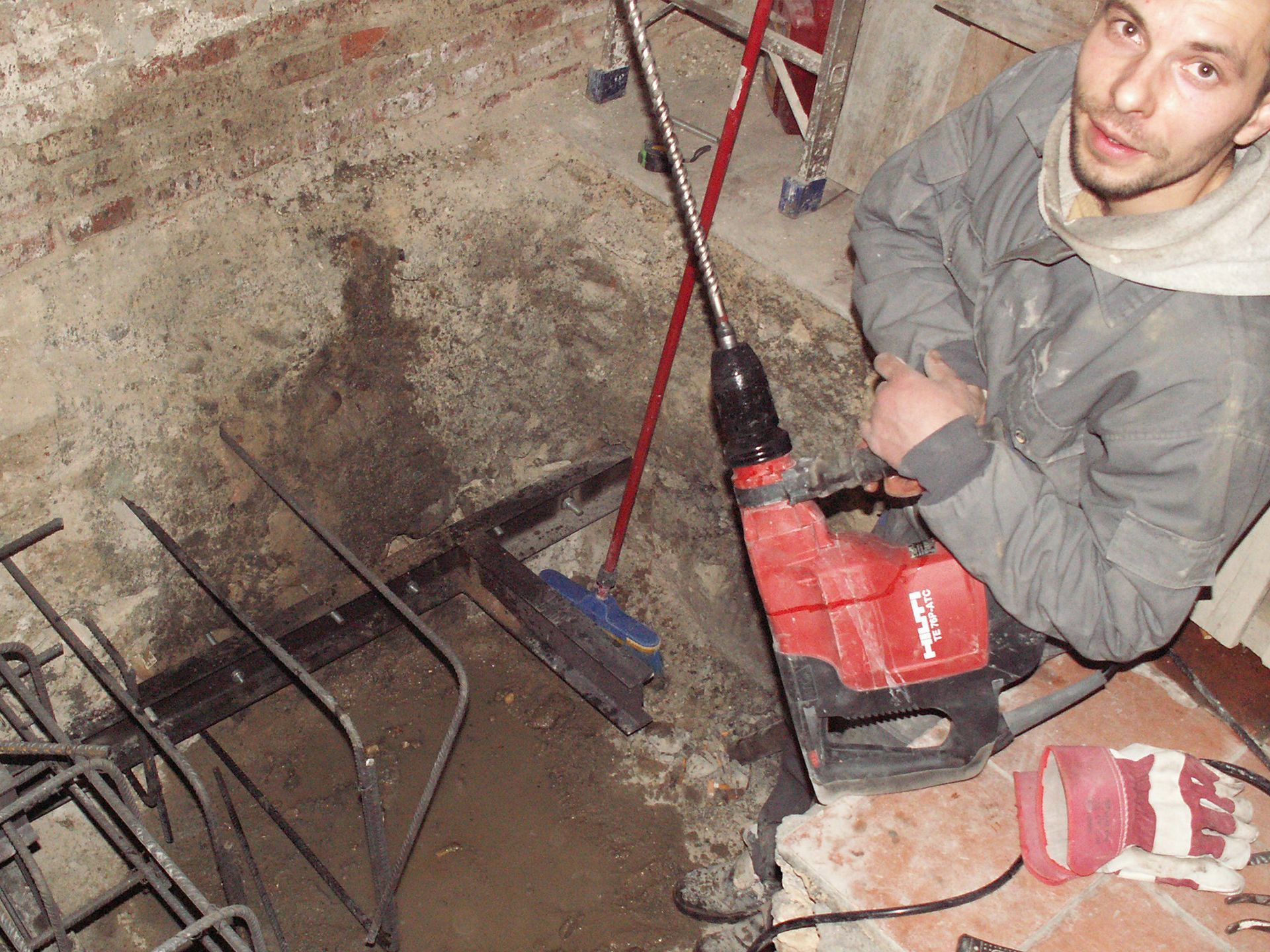 Un hombre está usando un taladro rojo que dice Hilti.