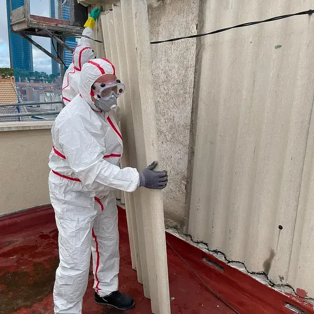 Un hombre con un traje de protección está de pie junto a una pared.