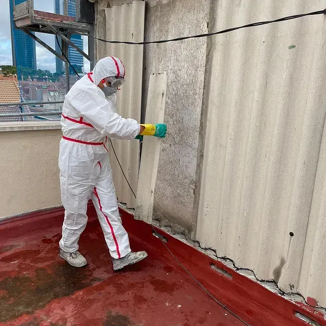 Un hombre con traje protector está pintando una pared.