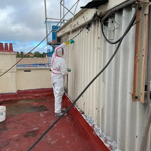 Un hombre con traje protector está pintando una pared.