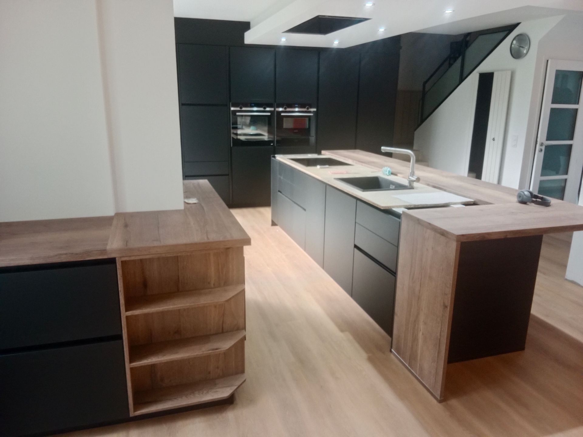 Cuisine moderne avec armoires noires, comptoirs en bois et îlot central.