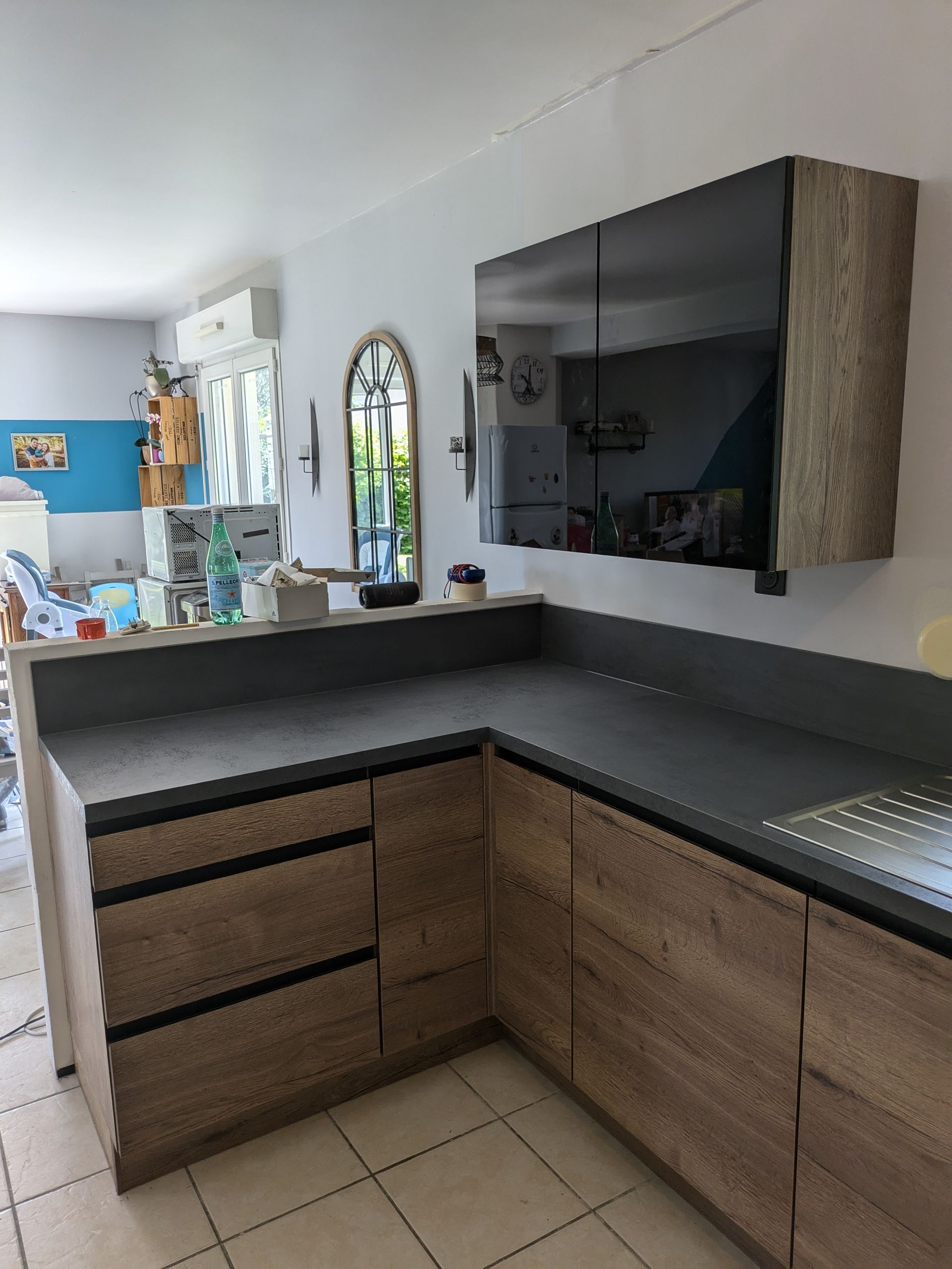 Cuisine moderne avec armoires en bois, comptoir foncé et armoire haute vitrée.