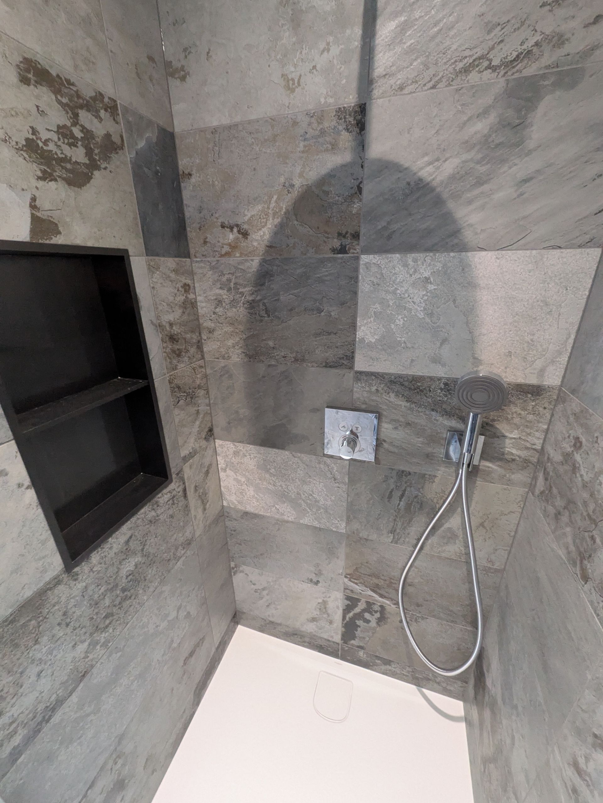 Salle de bains avec meuble-lavabo en bois, miroir, toilettes et plafond en pente.