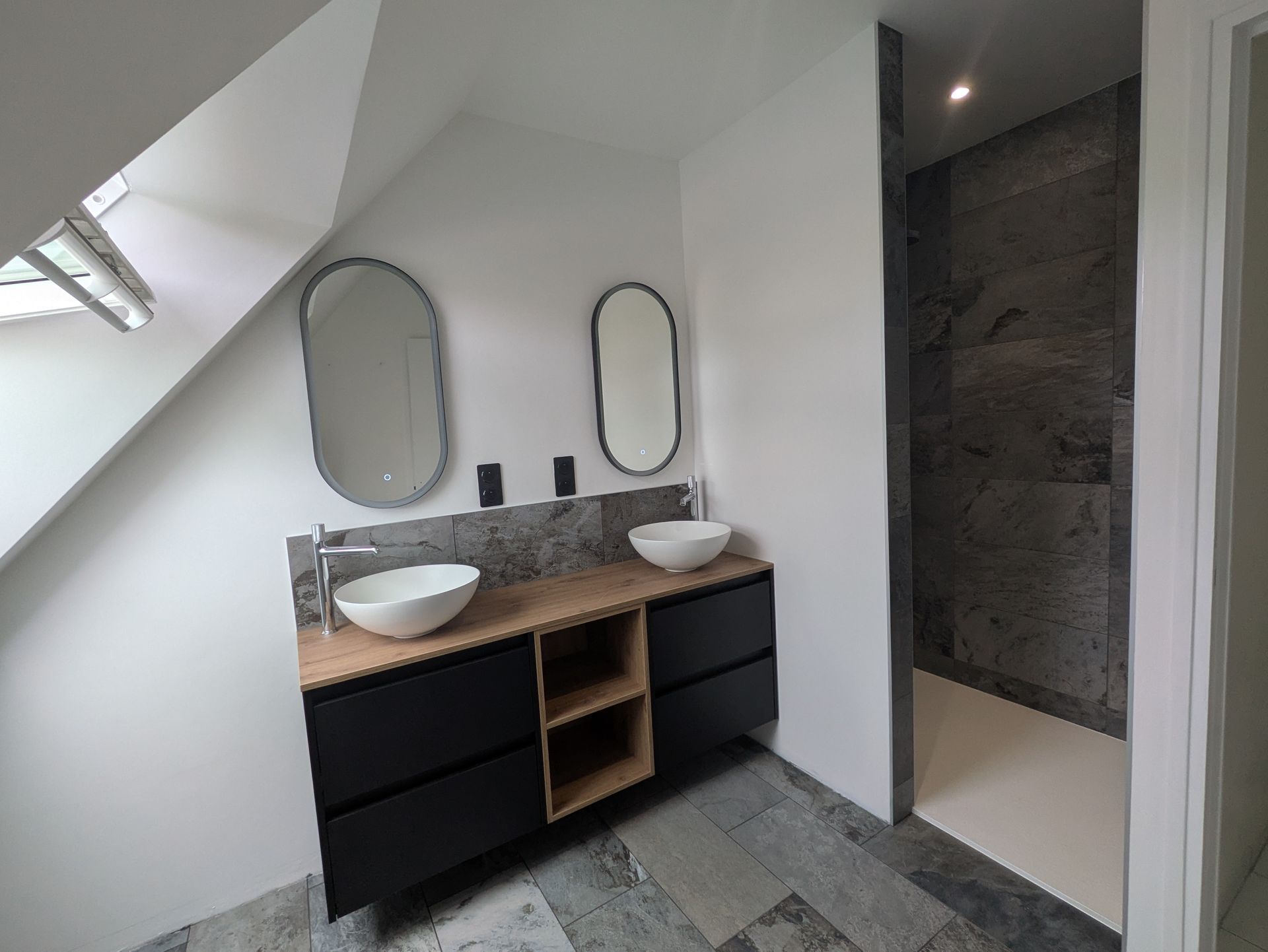 Salle de bains avec double vasque, deux miroirs ovales et une douche à l'italienne.