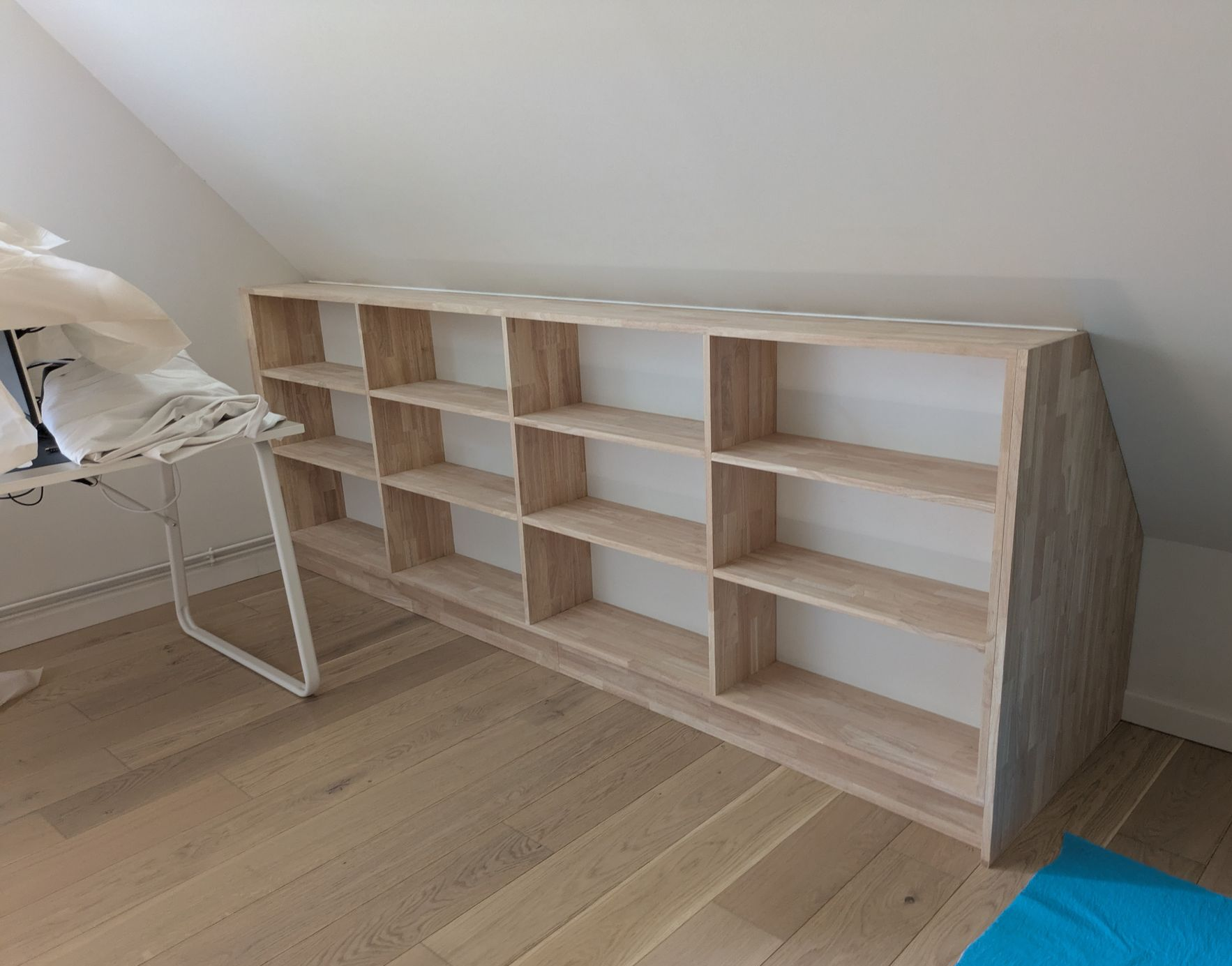 Placards de rangement blancs intégrés dans une pièce avec un plafond mansardé et un parquet clair.