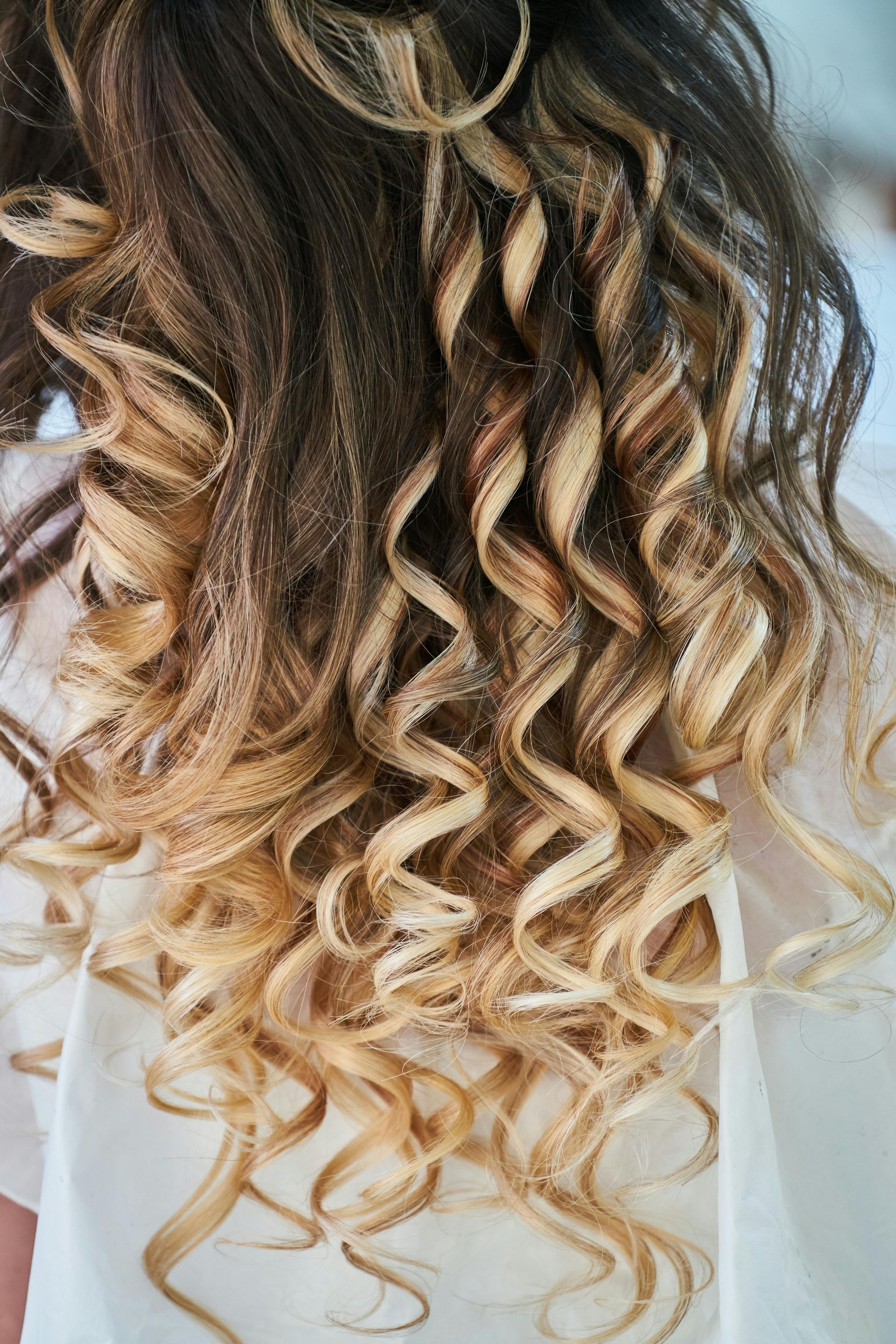 Una persona se lava el cabello en una peluquería. Un estilista con guantes negros aplica champú en el cabello de la clienta sobre un lavabo negro.