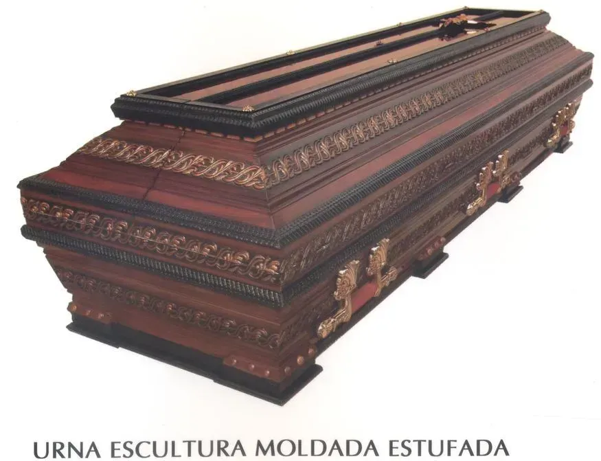 Caixão ornamentado de madeira escura com detalhes em ouro.