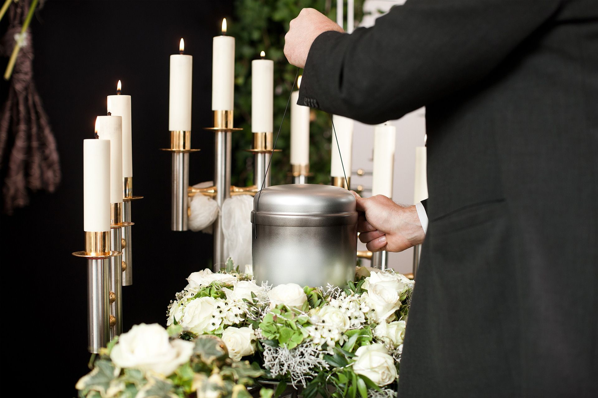 Silhueta de uma cruz no topo de uma colina contra um pôr do sol flamejante, com algumas figuras pequenas.