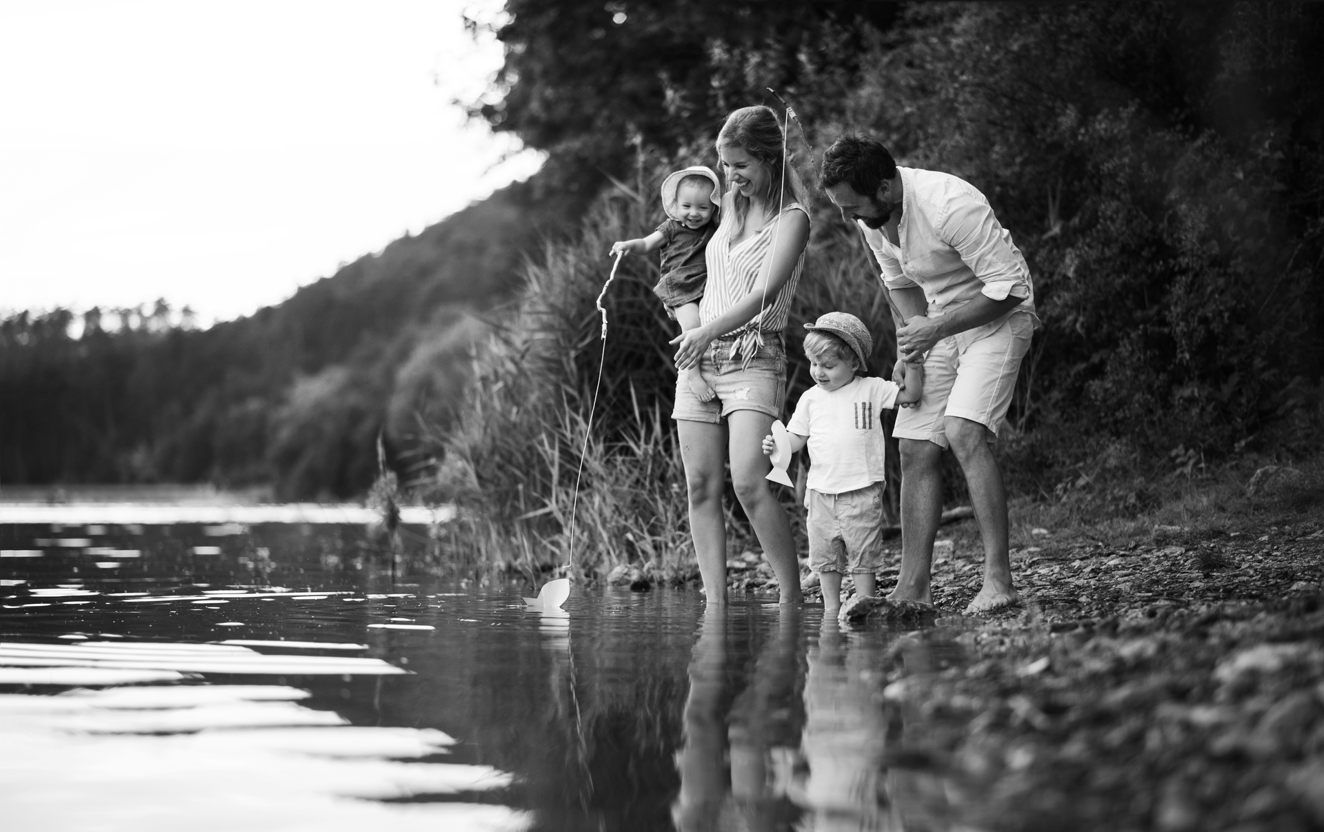 Une famille se tient ensemble dans l'eau peu profonde au bord d'un lac.