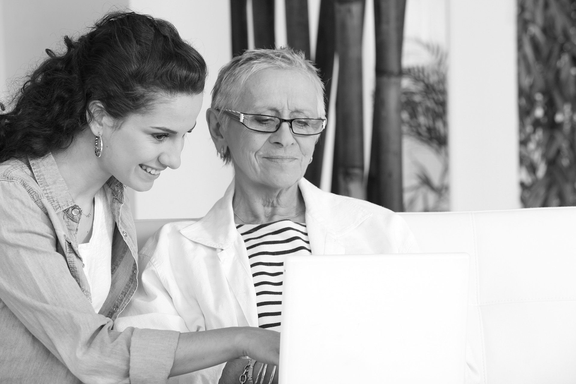 Deux personnes sont assises côte à côte, l'une pointant du doigt l'écran d'un ordinateur portable.
