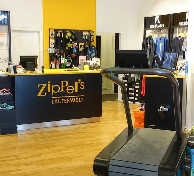 Innenansicht eines Laufschuhgeschäfts mit Kleiderständern, Postern und Schuhpräsentationen.