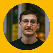 Ein Mann mit kurzen Haaren lächelt und trägt ein schwarzes Hemd mit dem Logo „ZipPel's Laufwelt“. Er steht vor einem Gebäude.