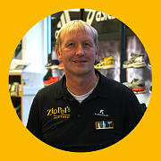 Ein Mann mit kurzen Haaren lächelt und trägt ein schwarzes Hemd mit dem Logo „ZipPel's Laufwelt“. Er steht vor einem Gebäude.