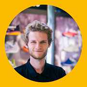 Ein Mann mit kurzen Haaren lächelt und trägt ein schwarzes Hemd mit dem Logo „ZipPel's Laufwelt“. Er steht vor einem Gebäude.