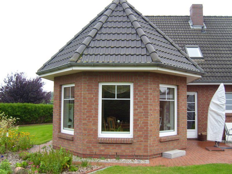 Ein Backsteinhaus mit grauem Dach und weißen Fenstern