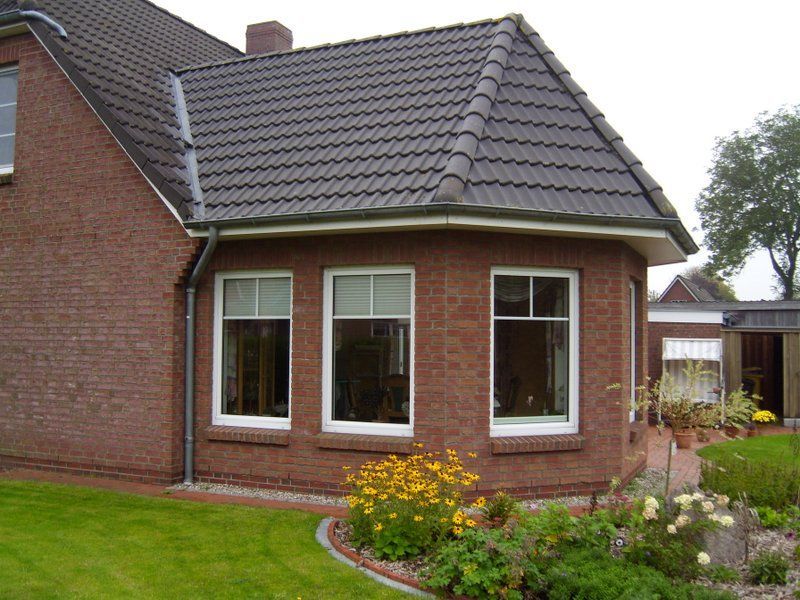 Ein Backsteinhaus mit schwarzem Dach und weißen Fenstern