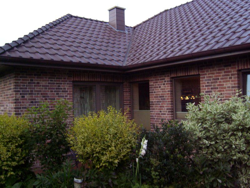 Ein Backsteinhaus mit einem braunen Dach und einem Schornstein