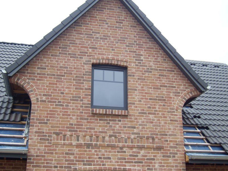 Ein Backsteingebäude mit einem schwarzen Dach und einem Fenster