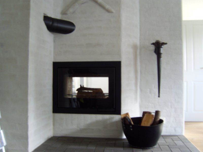 Ein Kamin mit einem Eimer Holzscheite davor