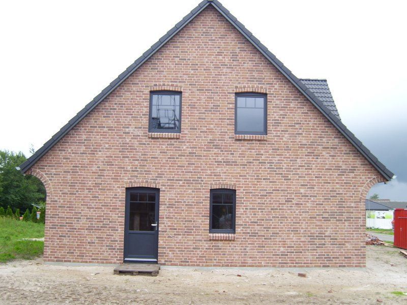 Ein Backsteinhaus mit zwei Fenstern und einer schwarzen Tür