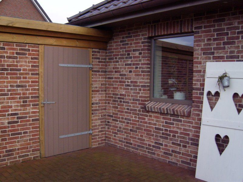 Ein Backsteingebäude mit einer Holztür und einem Fenster