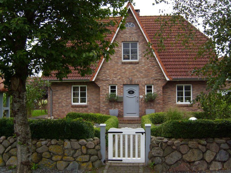 Ein Backsteinhaus mit einem weißen Tor davor