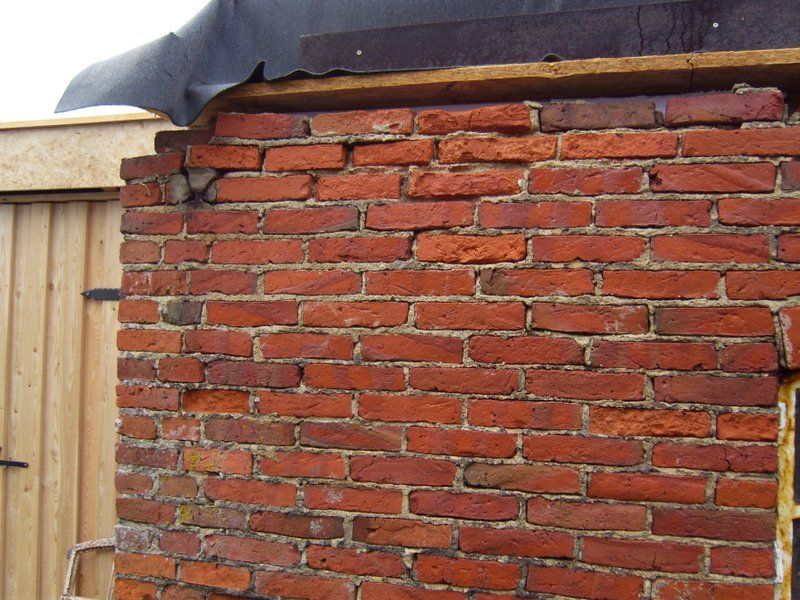 Eine Ziegelmauer mit einem Holzzaun im Hintergrund