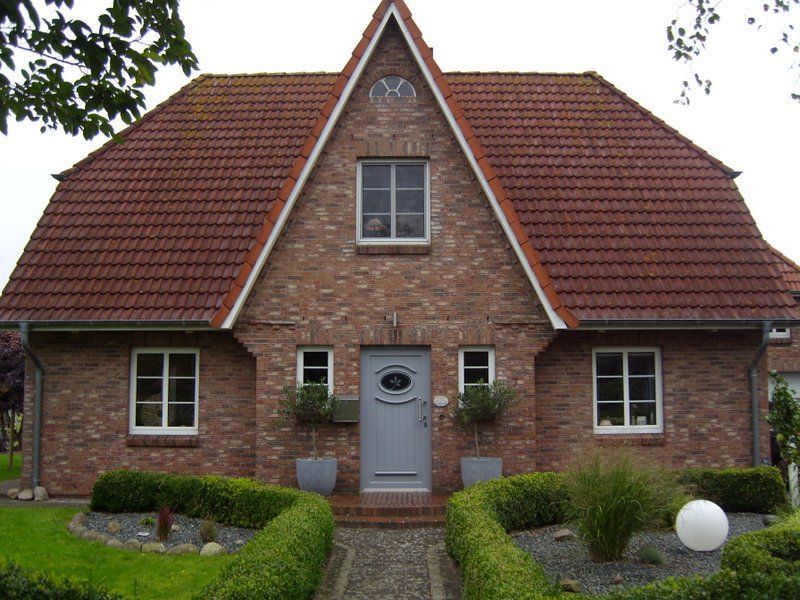 Ein Backsteinhaus mit einem roten Ziegeldach und einer blauen Tür