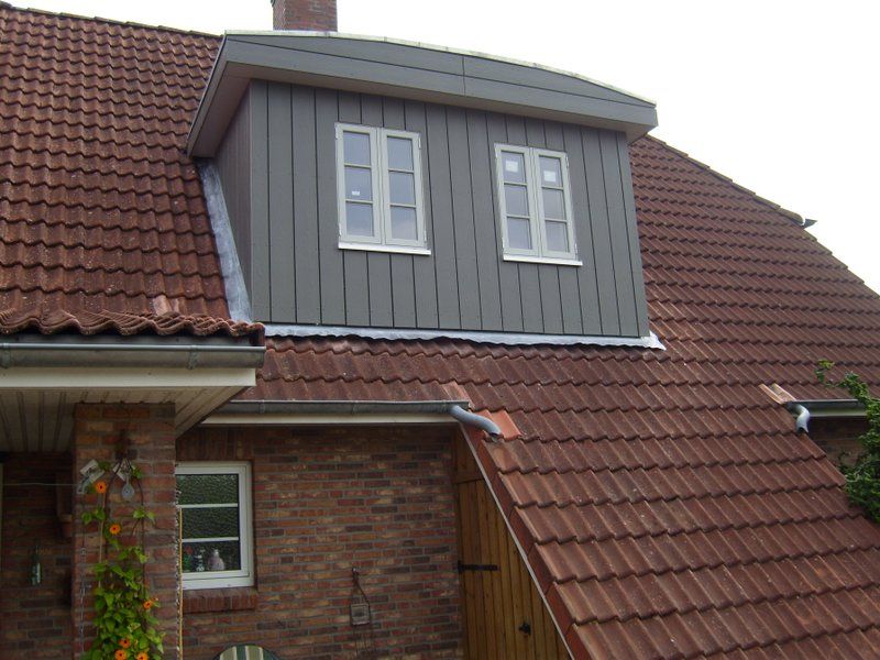 Ein Backsteinhaus mit einem Dach, auf dem sich ein Fenster befindet