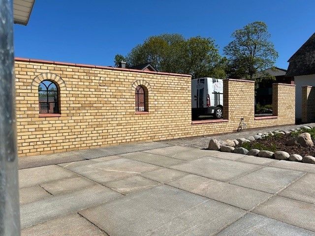 Eine Backsteinmauer mit einer Terrasse davor