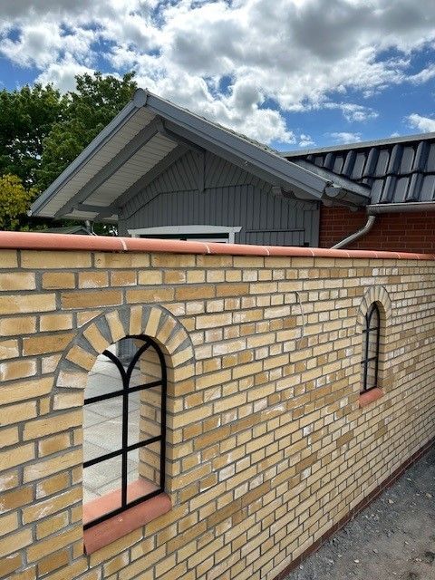 Eine Ziegelmauer mit Bogenfenstern und einem Dach im Hintergrund