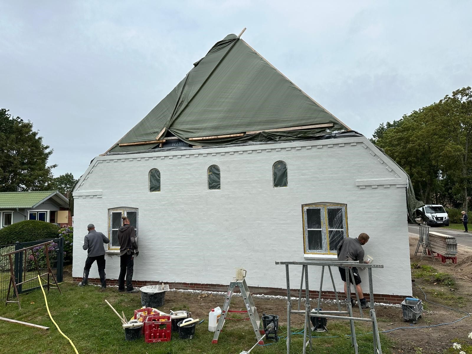 Eine Gruppe von Menschen streicht ein weißes Gebäude.