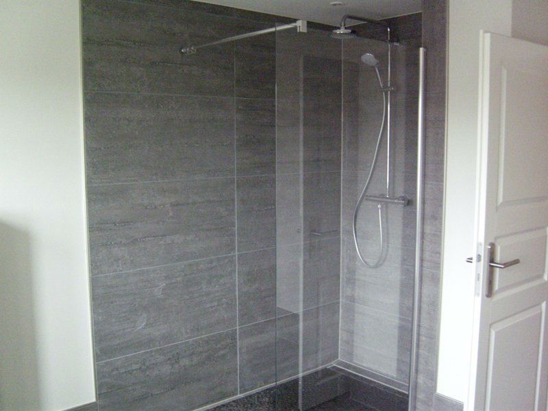 Ein Badezimmer mit ebenerdiger Dusche mit Glastür.