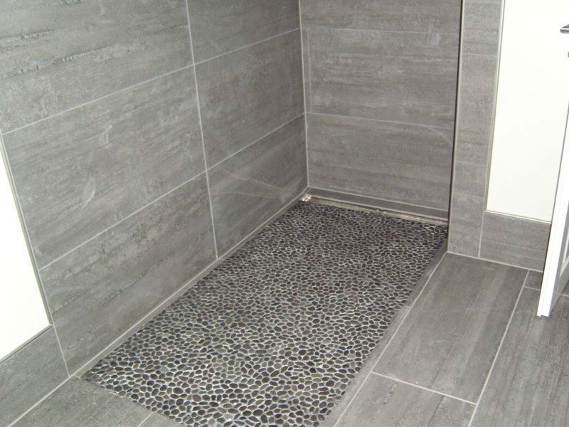 Ein Badezimmer mit ebenerdiger Dusche und gefliestem Boden