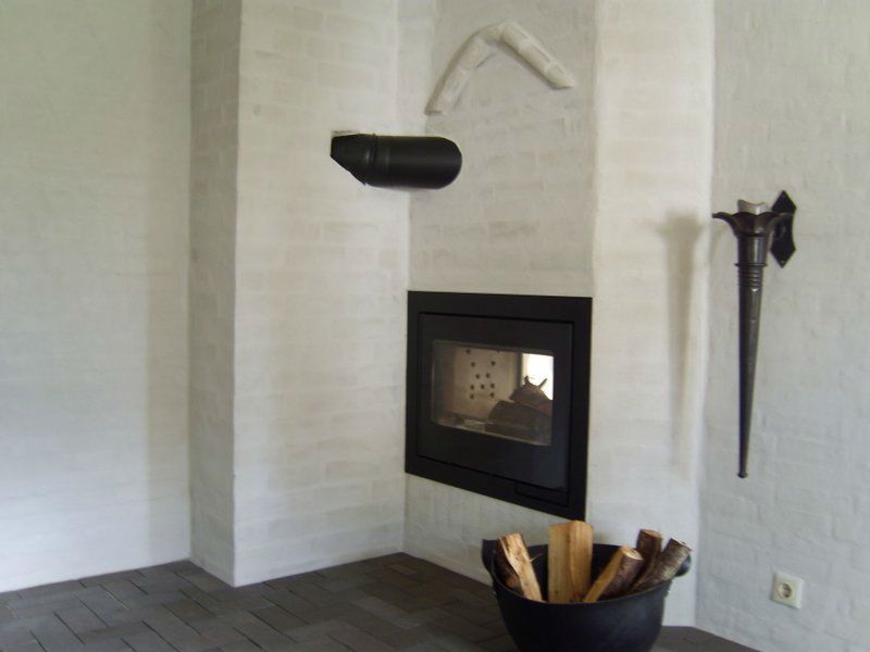 Ein Zimmer mit Kamin und einem Eimer Holzscheite