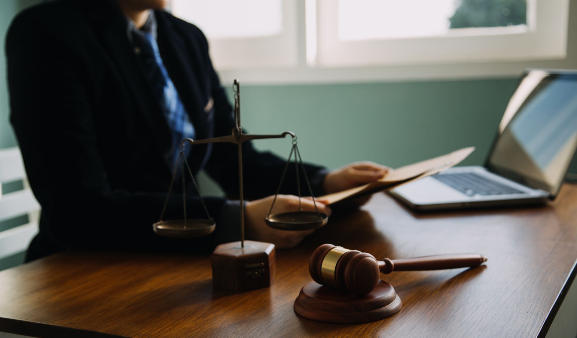 Escritorio de abogado con mazo, balanza de la justicia y computadora portátil en un entorno de oficina.
