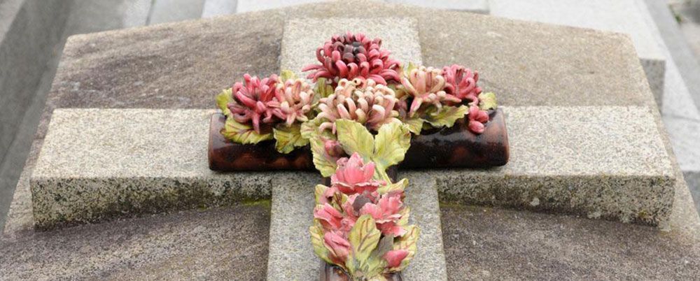 Tombe en pierre en forme de croix avec des fleurs colorées disposées au centre