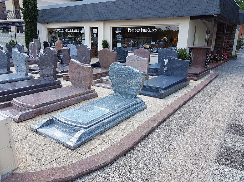 Exposition extérieure de pierres tombales en pierre et en bronze devant un bâtiment