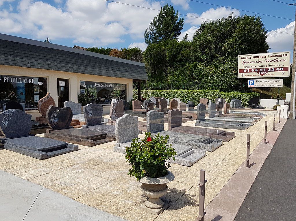 Présentoir extérieur en pierre et cristal à côté d'un bâtiment, avec un panneau et un aménagement paysager en gravier sous un ciel bleu