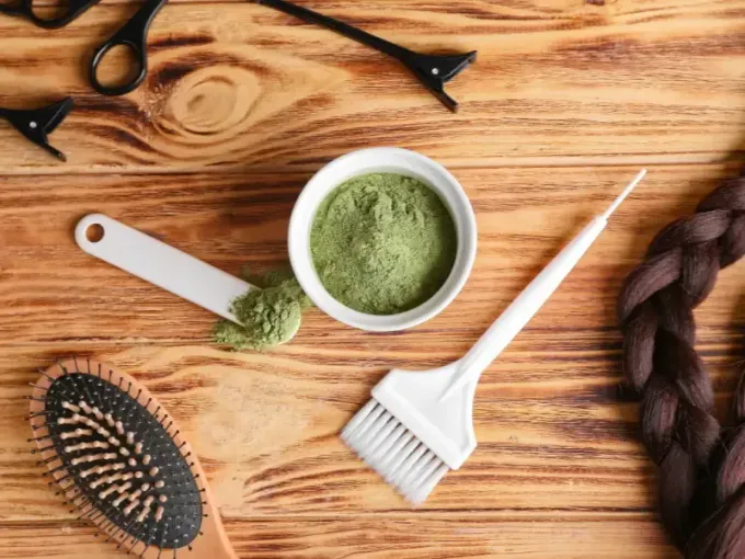 Herramientas para teñir el cabello: recipiente con polvo verde, cepillo, pala, peine, tijeras, pinzas para el cabello.