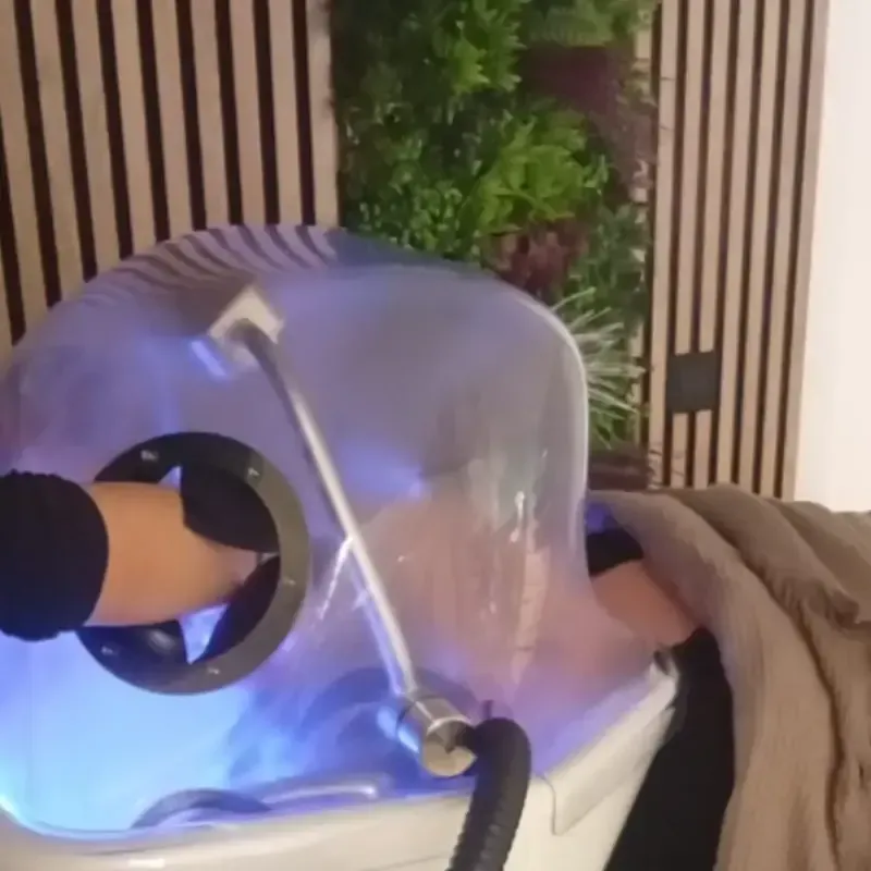 Mujer en el salón, mientras un estilista le lava el cabello.