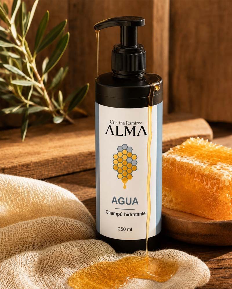 Botella de jabón líquido para manos ALMA Agua con etiqueta de panal junto a pan y tela sobre una mesa de madera.
